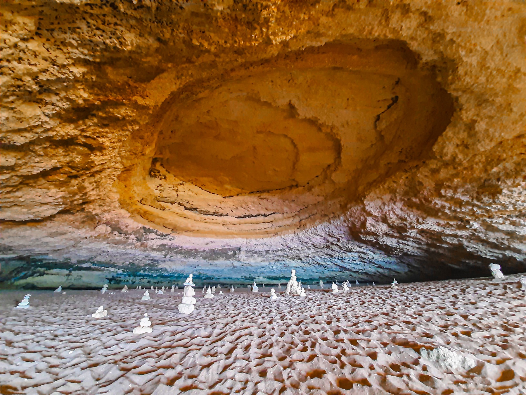 Vista de 2021 del interior de la cueva de Benagil, con luz solar, arena y visitantes; hoy está prohibido desembarcar en la arena.